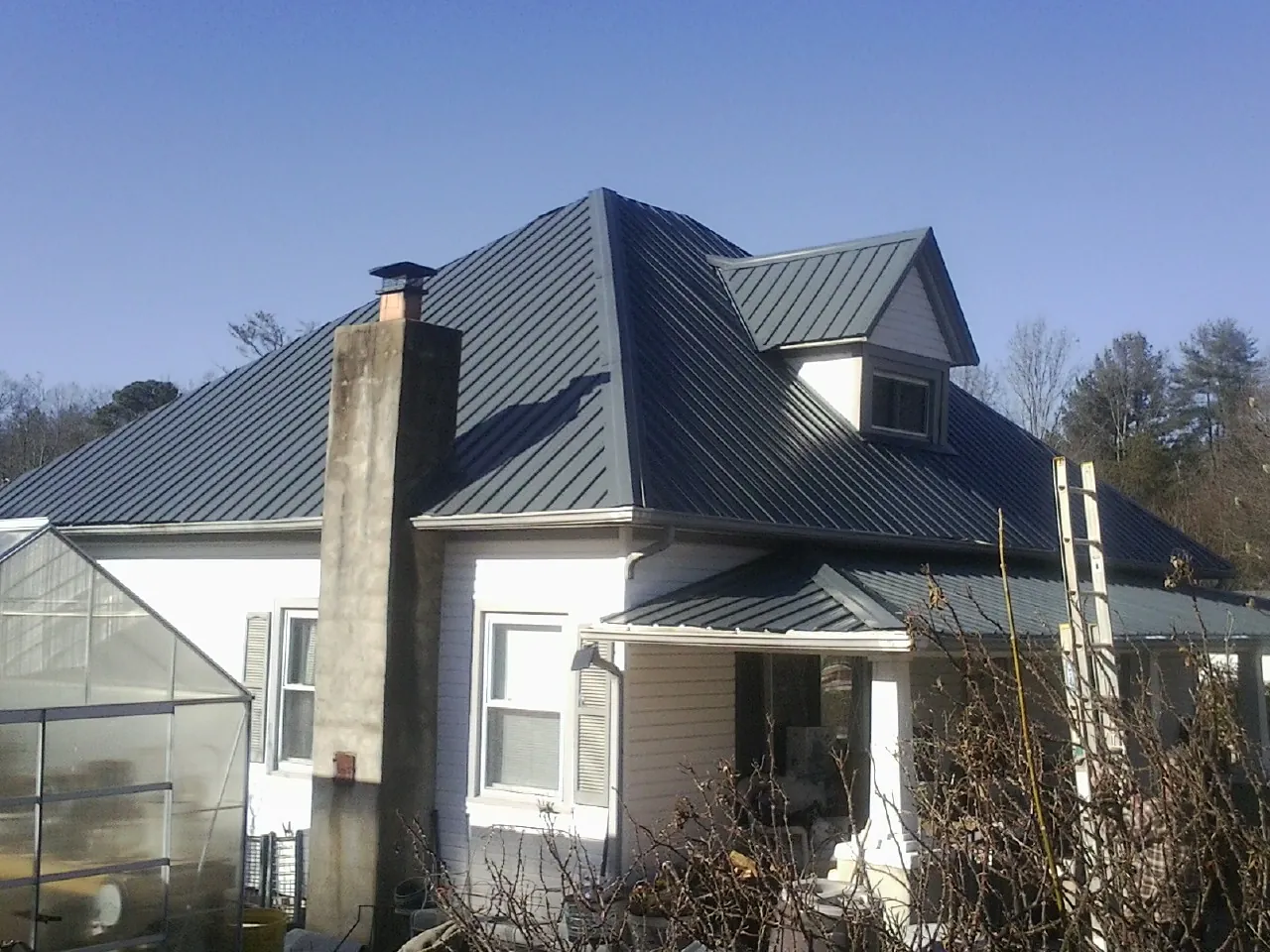 Dark blue standing seam metal roof on a white farmhouse with dormer — Slate & Tile Roof Repair by Roofing Brothers in East Mc Keesport