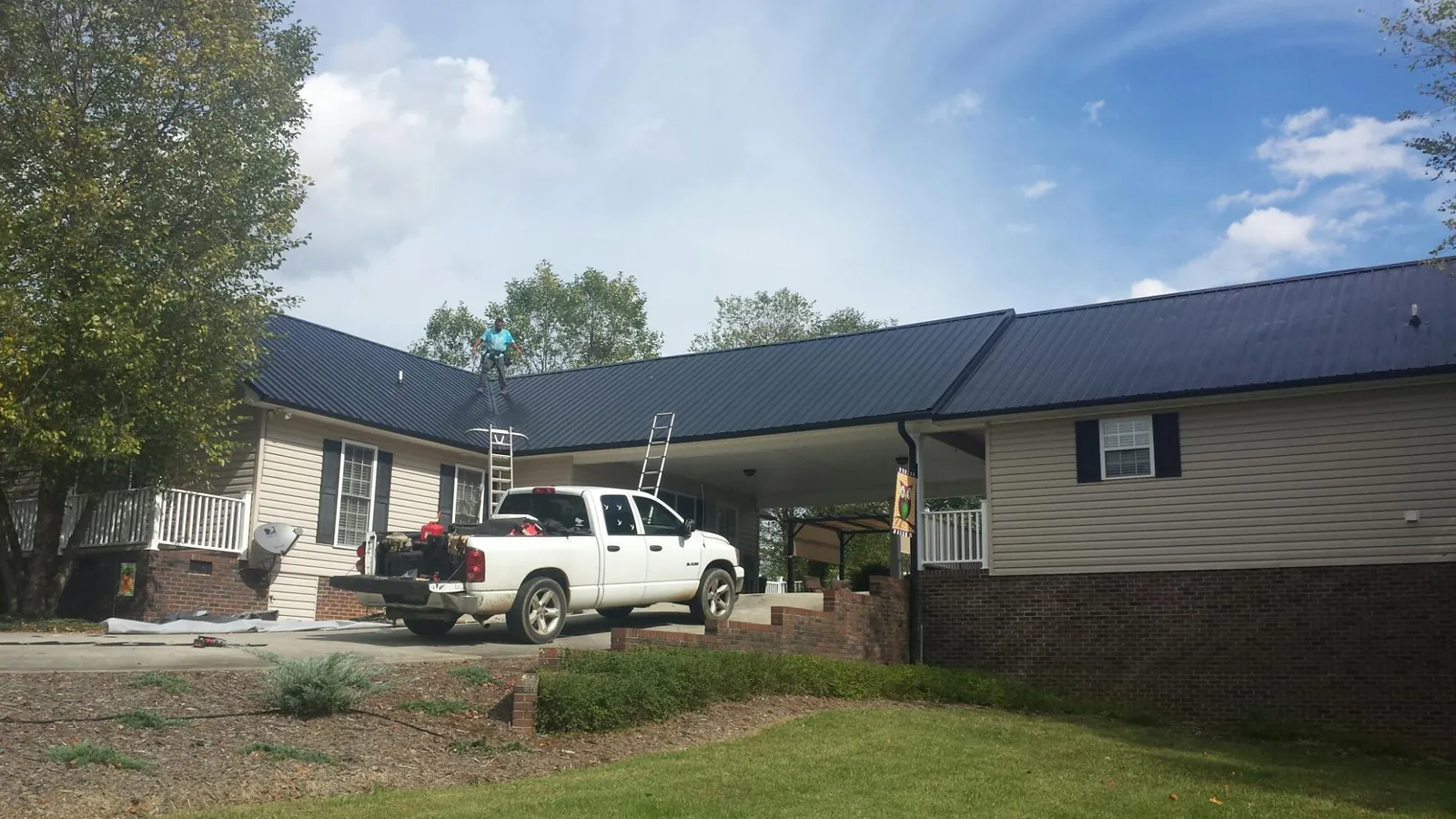Black metal roof over a home and attached breezeway with ladders set in East Mc Keesport