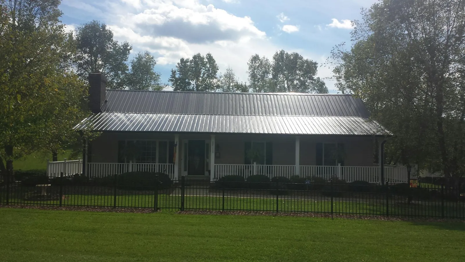 Gray metal roof on a brick ranch with a full width front porch — Gutter Guard Installation work by our crew in East Mc Keesport
