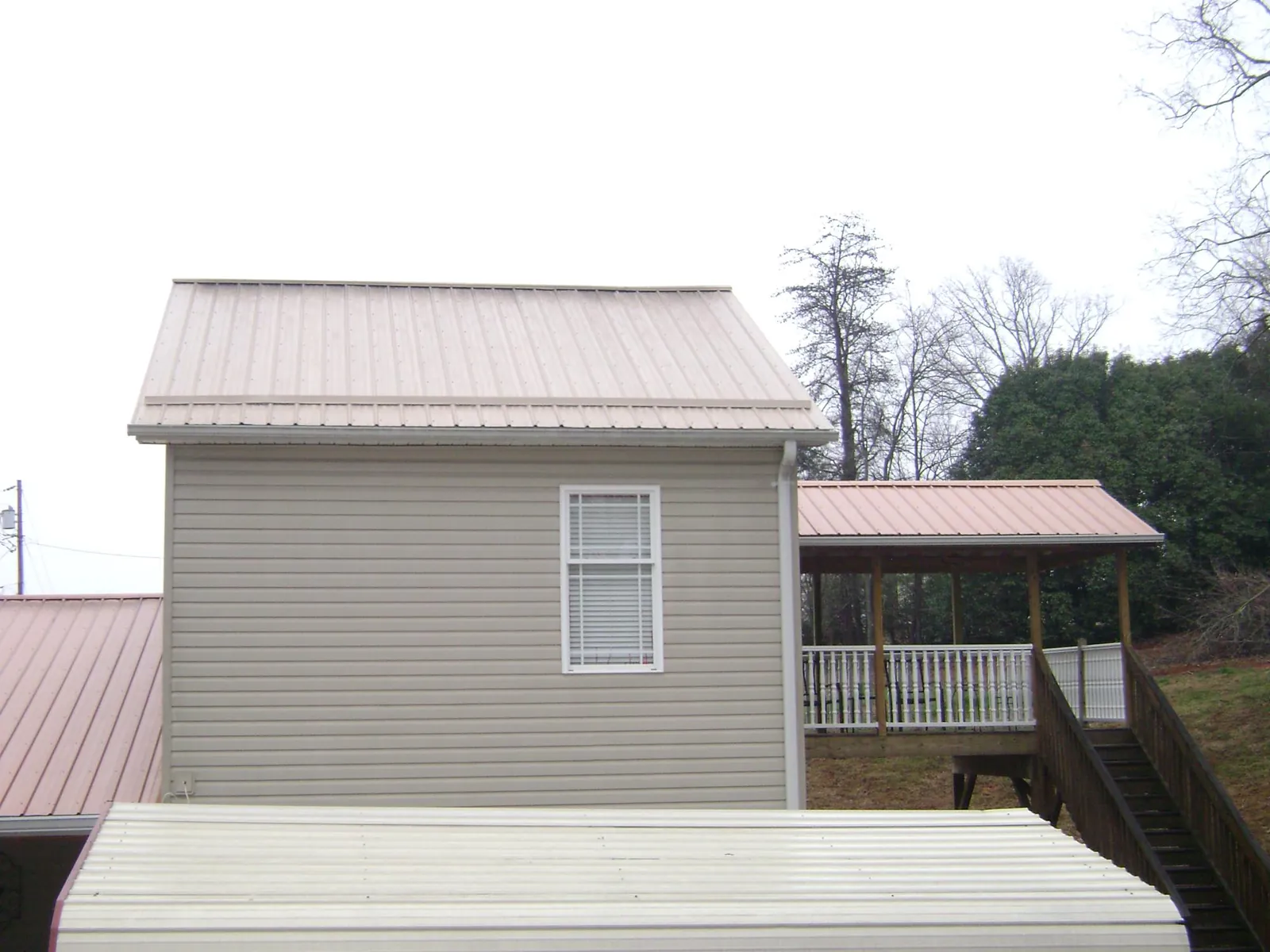 Tan metal roofs on a two story addition and attached porch, from a Roof Replacement job in East Mc Keesport