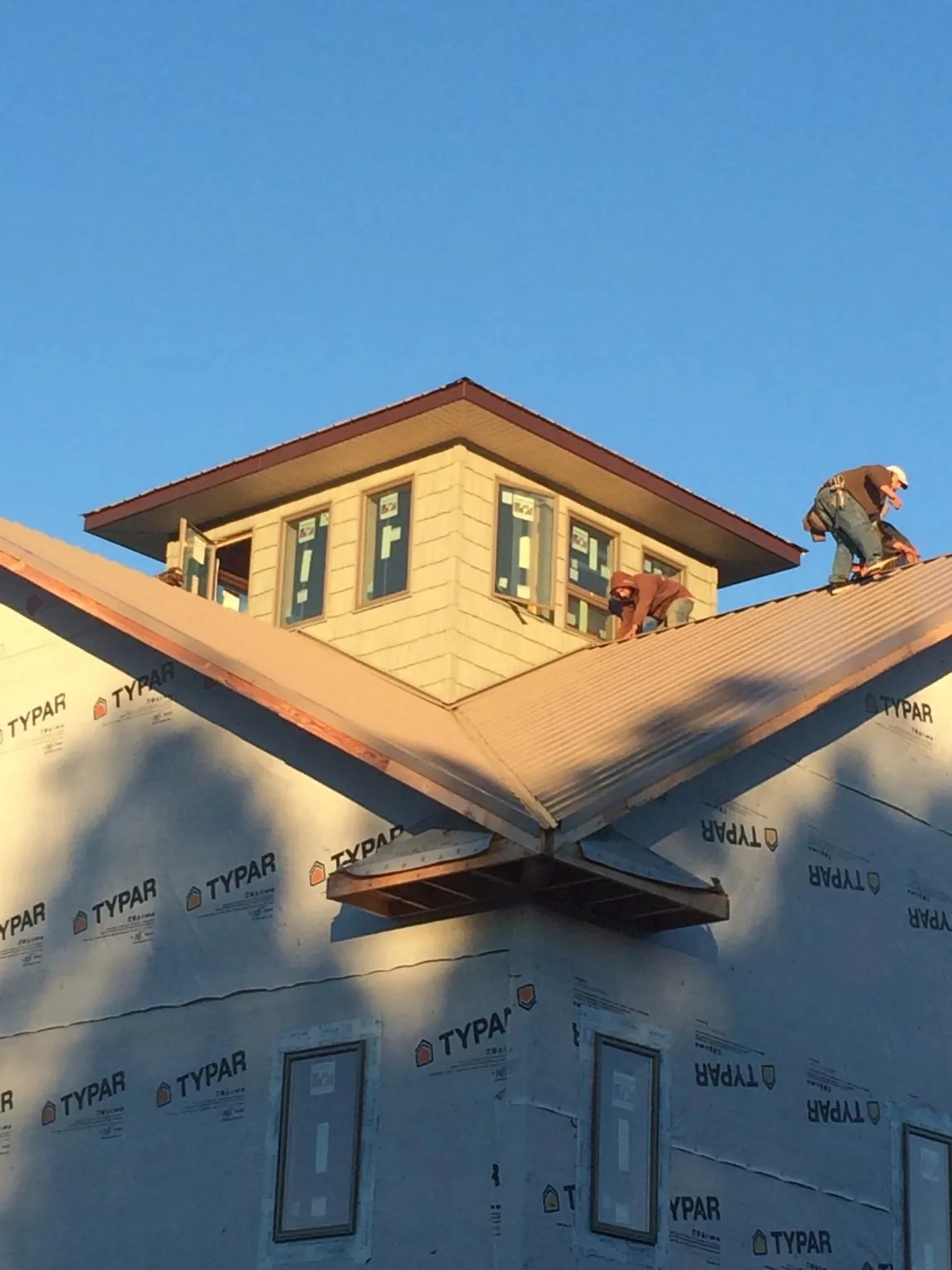 Roofers working around a rooftop cupola on a new metal roof at sunset — Roof Waterproofing in East Mc Keesport by Roofing Brothers